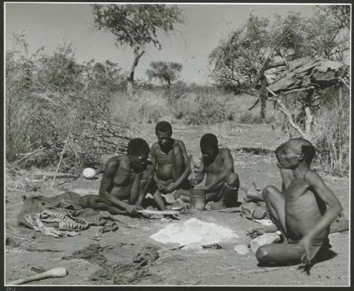 Groups [of] men: Group of men sitting around a fire, talking and working, including "Old Gau" (Band 1), ≠Gao (husband of Khwo//o-/Gasa and brother of "Old Gau"), /Gaishay, and "Qui /Navel" (print is a cropped image)