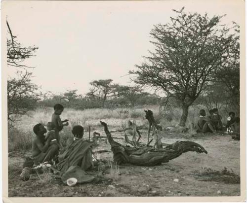 Band 1, an overnight encampment: ≠Toma sitting and kissing Norna, with !U sitting next to him, and other people in the background (print is a cropped image)