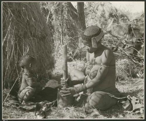 [No folder title]: //Kushay ("Gao Helmet's" second wife) pounding with mortar and pestle while her child watches (print is a cropped image)