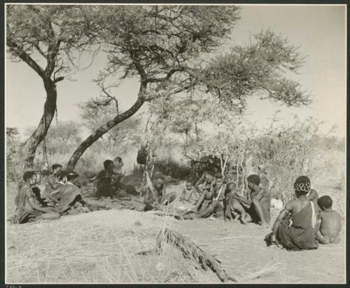 [No folder title]: "Gao Helmet" making an assegai head in his werft, with members of his band sitting around him (print is a cropped image)