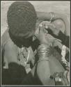 [No folder title]: Woman's hands fixing another woman's earring (print is a cropped image)