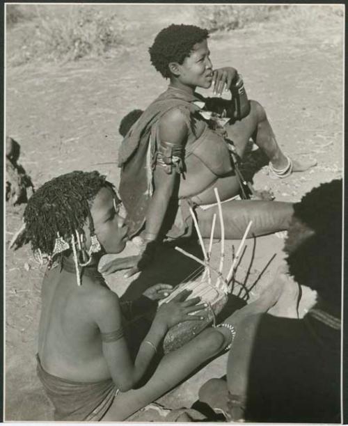 [No folder title]: "Little N!ai" playing the //guashi, with Khuan//a (daughter of "Old /Gaishay" and sister of "Gao Medicine") sitting behind her (print is a cropped image)