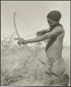 [No folder title]: "/Qui Hunter" holding a bow and arrow, showing method of holding and releasing (print is a cropped image)