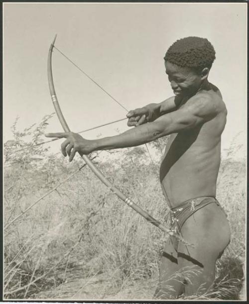 [No folder title]: "/Qui Hunter" holding a bow and arrow, showing method of holding and releasing (print is a cropped image)