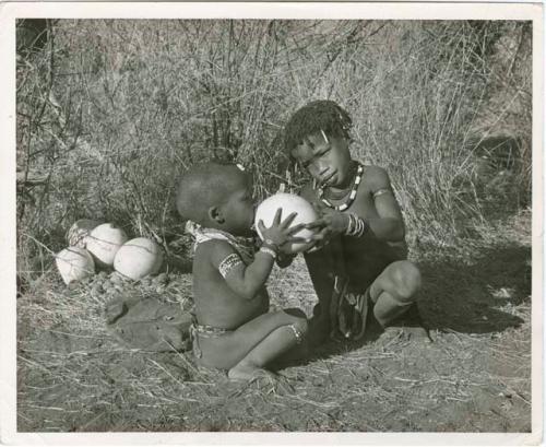 N!ai with children: "Little N!ai" giving /Gaishay a drink from an ostrich eggshell (print is a cropped image)