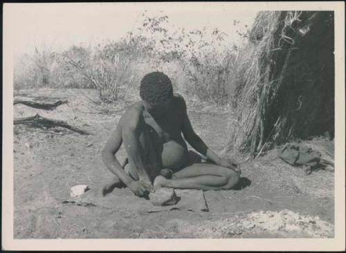 Man sitting in front of a skerm smoothing something, possibly an arrow foreshaft