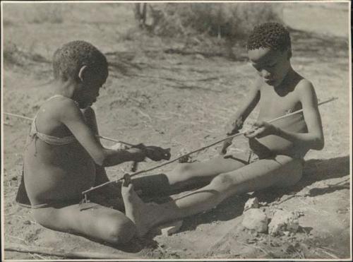 Tsamgao (son of ≠Toma), and one of Gau's sons from Band 2 peeling sticks with which to toss the djani (helicopter toy)
