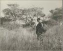 Woman with a child on her back walking in the grass
