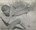 Gau's son shooting a slingshot made from a piece of an old inner tube