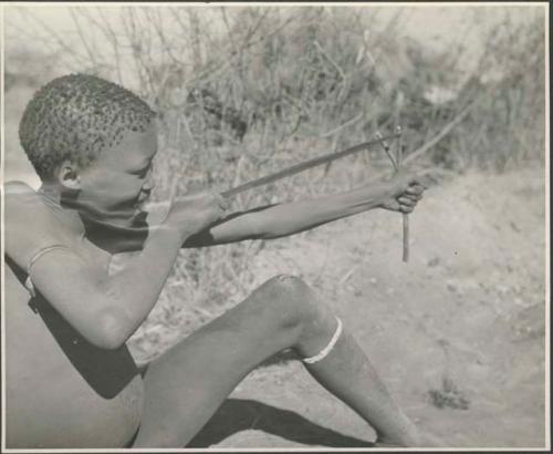 Gau's son shooting a slingshot made from a piece of an old inner tube