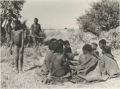 Group of women sitting in the dance circle, with one of the dancing men approaching