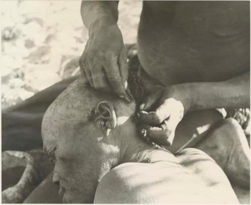 !Gai seated, cutting another man's hair, close-up




