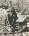 Oukwane playing a musical bow, seated
