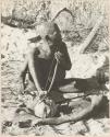 Oukwane playing a musical bow, seated
