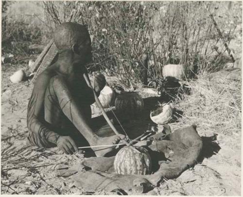 Oukwane playing a musical bow, seated
