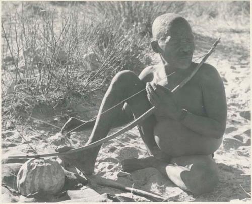 Oukwane playing a musical bow, seated
