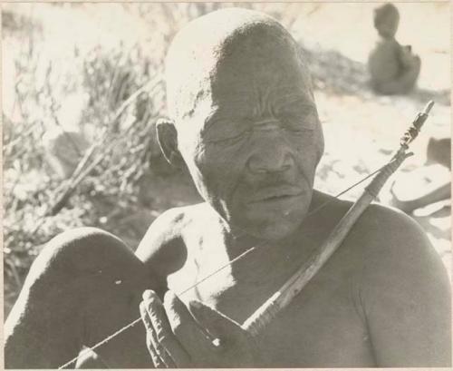 Close-up of Oukwane playing a musical bow, seated
