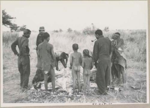 Men skinning a gemsbok, surrounded by a group of people watching
