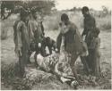 Men skinning a gemsbok, surrounded by a group of people watching