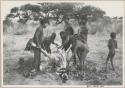 Men skinning a gemsbok, with a group of people watching