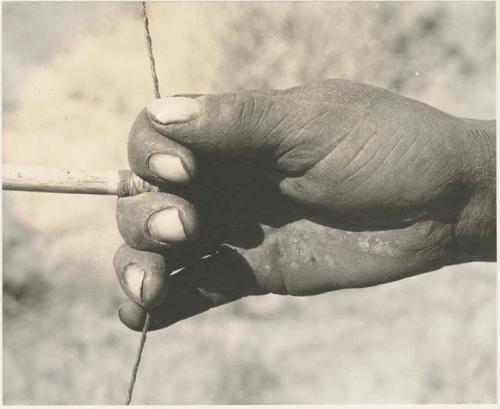 Close-up of !Gai's right hand holding arrow to release