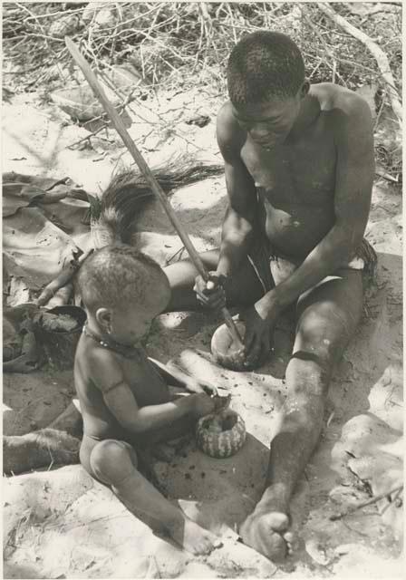 !Gai and N!whakwe with tsama melons sitting at their place in the werft


