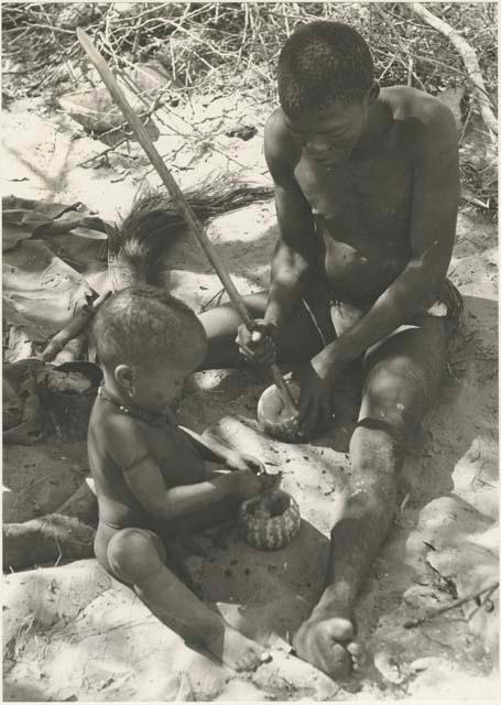 !Gai and N!whakwe with tsama melons sitting at their place in the werft


