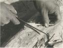 Close-up of a person's hands sharpening an arrow



