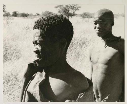 Oukwane and !Gai standing in grass, close-up
