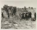 Oukwane, !Gai, and expedition members standing around expedition Jeep