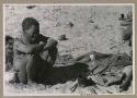 Oukwane sitting, with his possessions on the ground next to him
