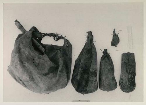 Five skin bags used to contain /Twikwe's possessions, including a ≠dobe, made of steenbok skin, with a scraper in it, and 4 /twam of different sizes, with a ruler for measurement