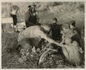 Oukwane and other people sitting and talking to William Donnellan and Elizabeth Marshall Thomas, with Wilhelm Camm interpreting. Oukwane is naming the internal parts of an animal