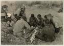 Oukwane and other people sitting and talking to William Donnellan and Elizabeth Marshall Thomas, with Wilhelm Camm interpreting. Oukwane is naming the internal parts of an animal