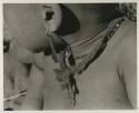 N!whakwe wearing a necklace and earring, close-up