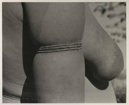 Woman wearing thong bracelets on her upper arm, close-up