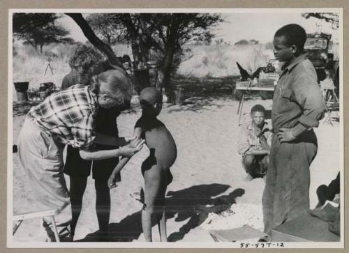 Child having their skin color documented by Lorna Marshall, with Kernel Ledimo watching