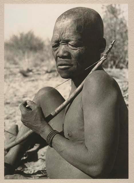 Close-up of Oukwane seated, playing a bow

