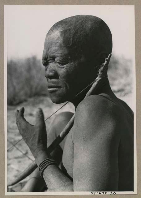 Close-up of Oukwane seated, playing a bow

