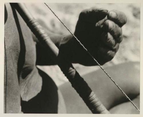 Close-up of Oukwane's hand demonstrating how to play a musical bow

