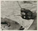 Close-up of Oukwane's hand demonstrating how to play a musical bow


