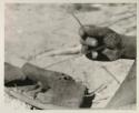 Close-up of Oukwane's hand and foot demonstrating how to play a musical bow

