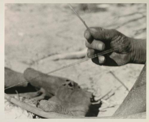 Close-up of Oukwane's hand and foot demonstrating how to play a musical bow

