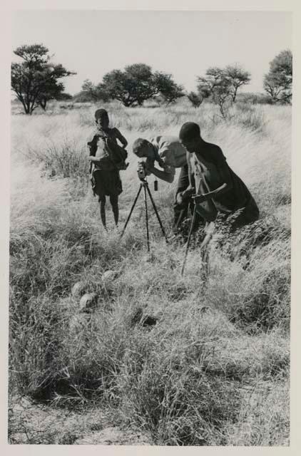 /Twikwe and DaSi!Na standing beside John Marshall while he films

