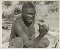 Visiting man demonstrating hunting hand signals, half figure seated