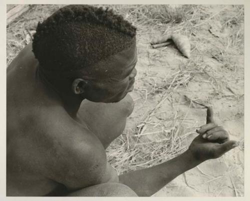 Visiting man demonstrating huntinghand signals, half figure seated
