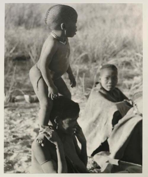 N!whakwe standing on his mother Tsekue's shoulders
