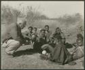 [No folder title]: Gau, "Old ≠Toma," /Gam and //Khuga (wife of !Naishi) sitting with Laurence Marshall (print is a cropped image)