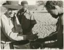 [No folder title]: Group of men receiving food from Lorna Marshall (print is a cropped image)