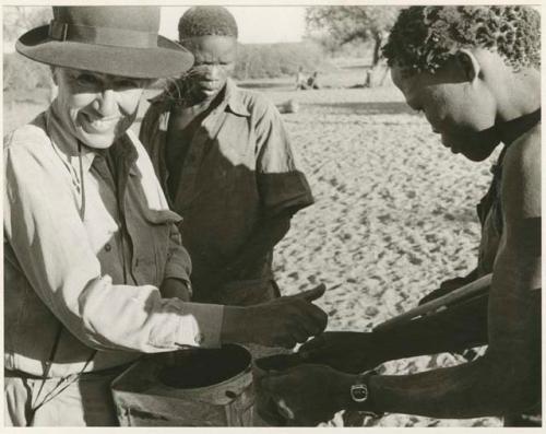 [No folder title]: Group of men receiving food from Lorna Marshall (print is a cropped image)